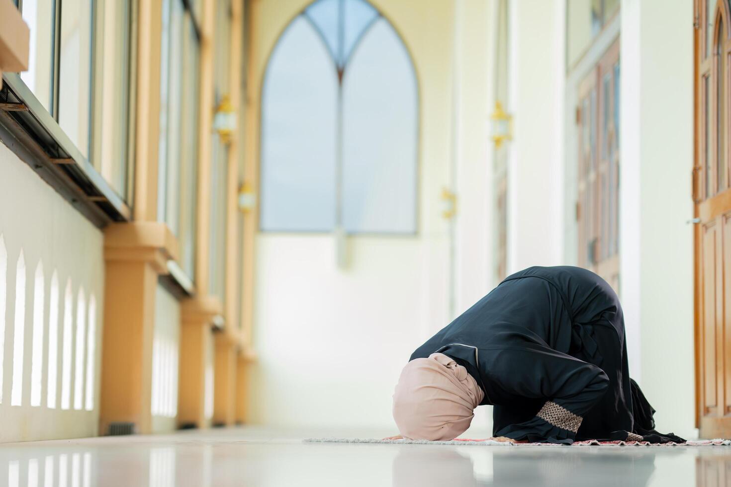 The image of an Asian Muslim woman in the Islamic religion in hijab in cream color. She was praying in a beautiful mosque out of respect for God. photo