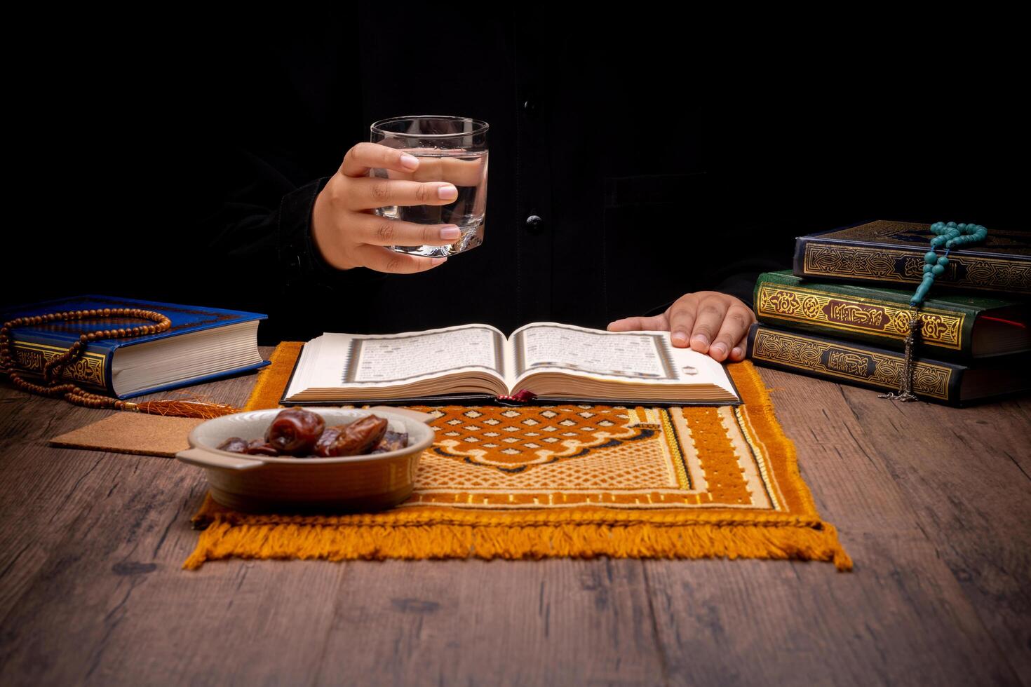 Many Date Palms are on bowls, plates, and cups of water, and the Quran is on wooden tables, to wait for the time of Iftar, with the concept of ramadan Muslims, Arabic calligraphy meaning of Al Quran photo