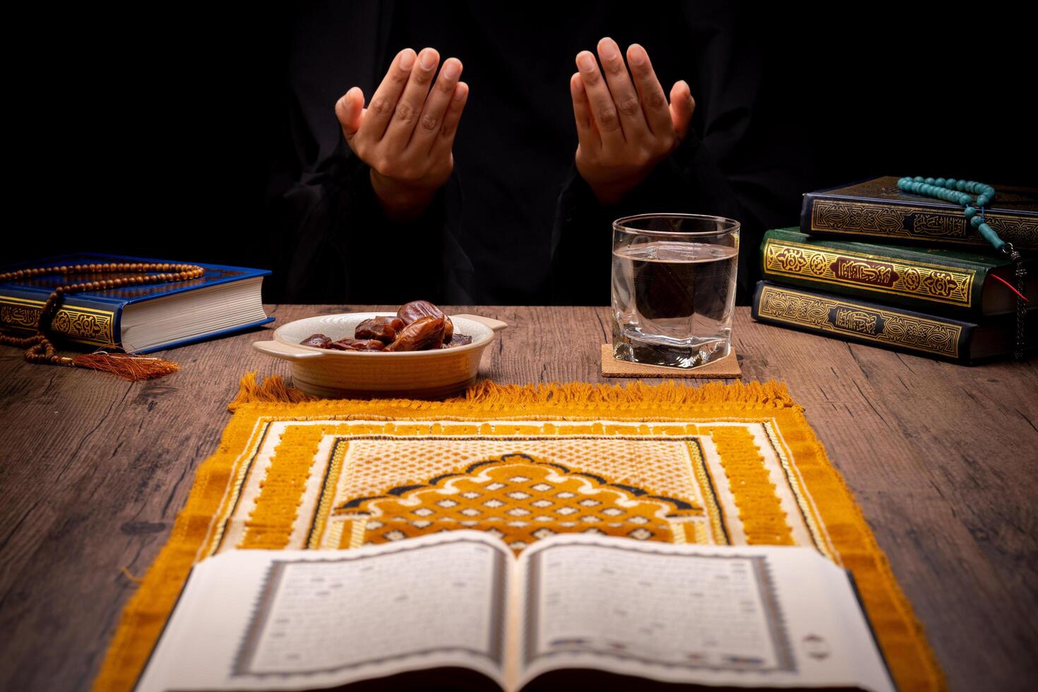 Many Date Palms are on bowls, plates, and cups of water, and the Quran is on wooden tables, to wait for the time of Iftar, with the concept of ramadan Muslims, Arabic calligraphy meaning of Al Quran photo