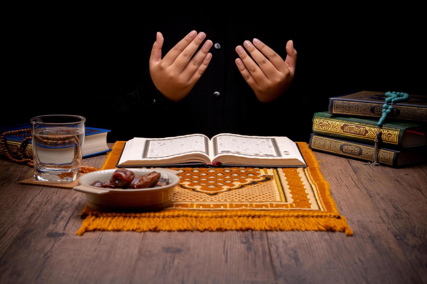 Many Date Palms are on bowls, plates, and cups of water, and the Quran is on wooden tables, to wait for the time of Iftar, with the concept of ramadan Muslims, Arabic calligraphy meaning of Al Quran photo