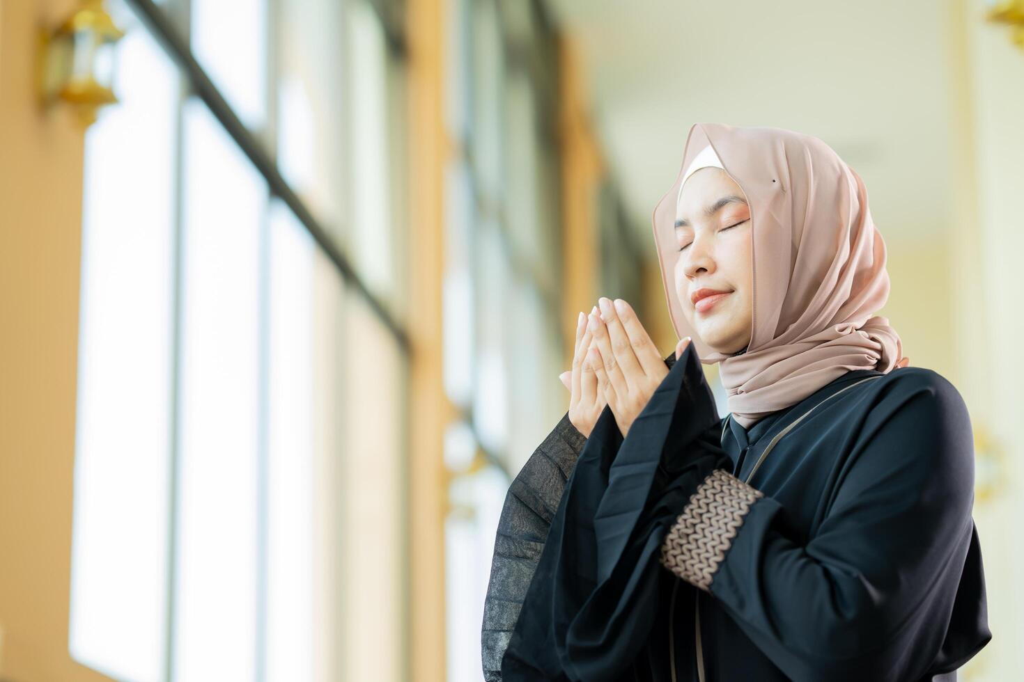 The image of an Asian Muslim woman in the Islamic religion in hijab in cream color. She was praying in a beautiful mosque out of respect for God. photo