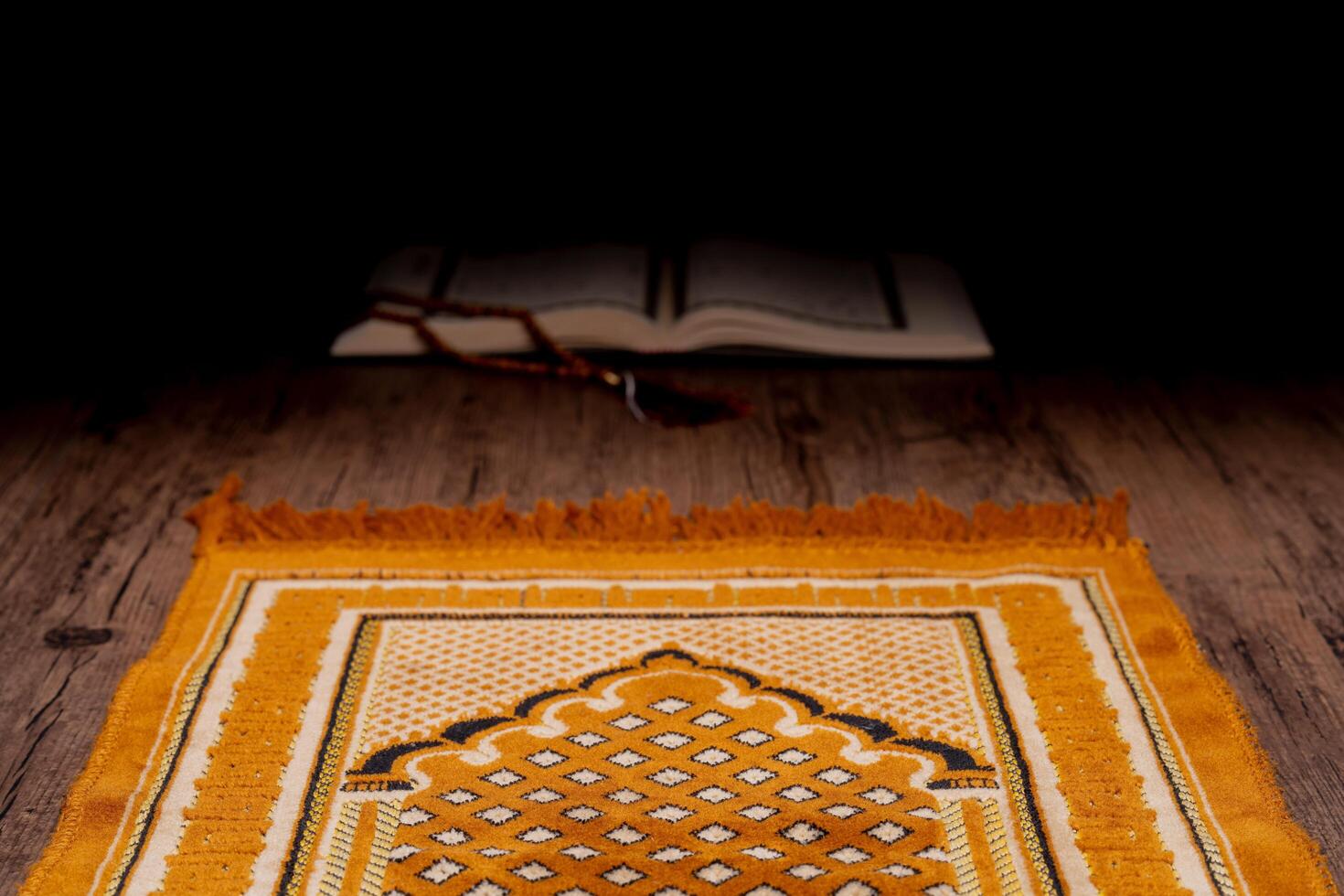 A Asian Muslim woman is sitting and reading the Quran at the wooden table at his house during the night during the month of ramadan, Arabic calligraphy meaning of Al Quran. photo