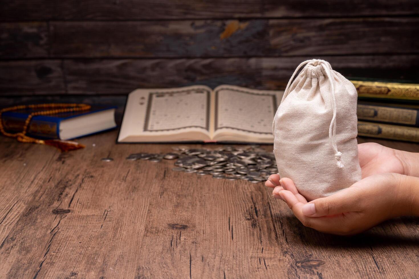 Hands holding a wooden bowl of rice grains and money bag for zakat, Islamic zakat concept. Muslims help the poor and needy. Conceptual shoot for property, income, and fitrah zakat. photo