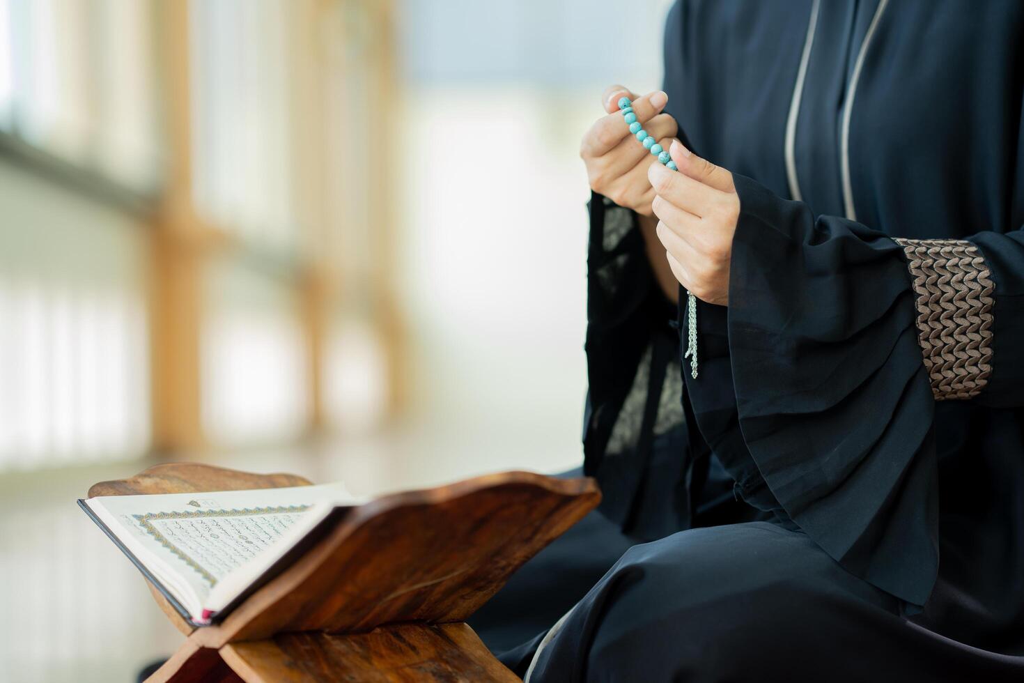 The image of an Asian Muslim woman in the Islamic religion in hijab in cream color. reading the Quran and having a happy smiling face Staying in a beautiful mosque out of respect for God. photo