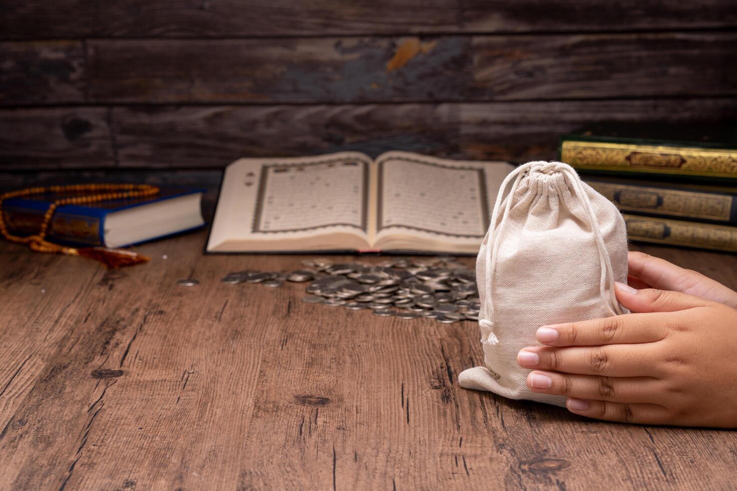 Hands holding a wooden bowl of rice grains and money bag for zakat, Islamic zakat concept. Muslims help the poor and needy. Conceptual shoot for property, income, and fitrah zakat. photo