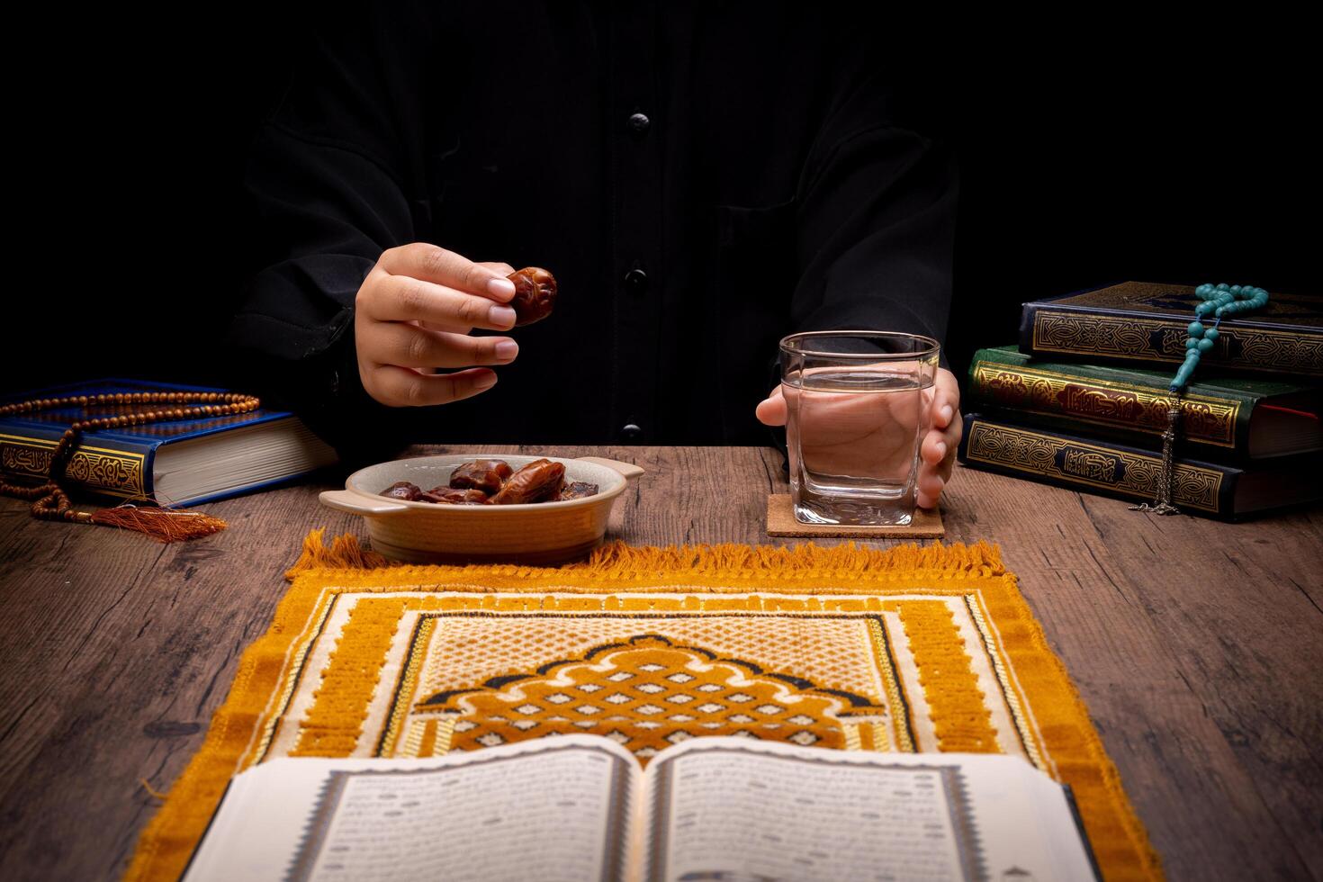 Many Date Palms are on bowls, plates, and cups of water, and the Quran is on wooden tables, to wait for the time of Iftar, with the concept of ramadan Muslims, Arabic calligraphy meaning of Al Quran photo
