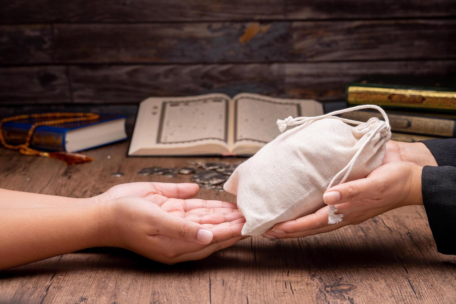 Hands holding a wooden bowl of rice grains and money bag for zakat, Islamic zakat concept. Muslims help the poor and needy. Conceptual shoot for property, income, and fitrah zakat. photo