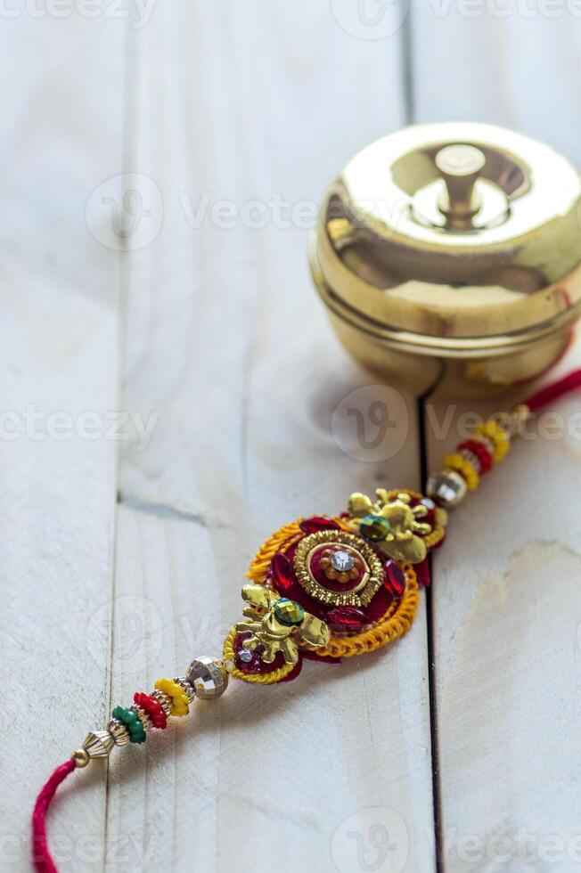 Indian festival Raksha Bandhan background with an elegant Rakhi, Rice Grains and Kumkum. A traditional Indian wrist band which is a symbol of love between Brothers and Sisters. photo
