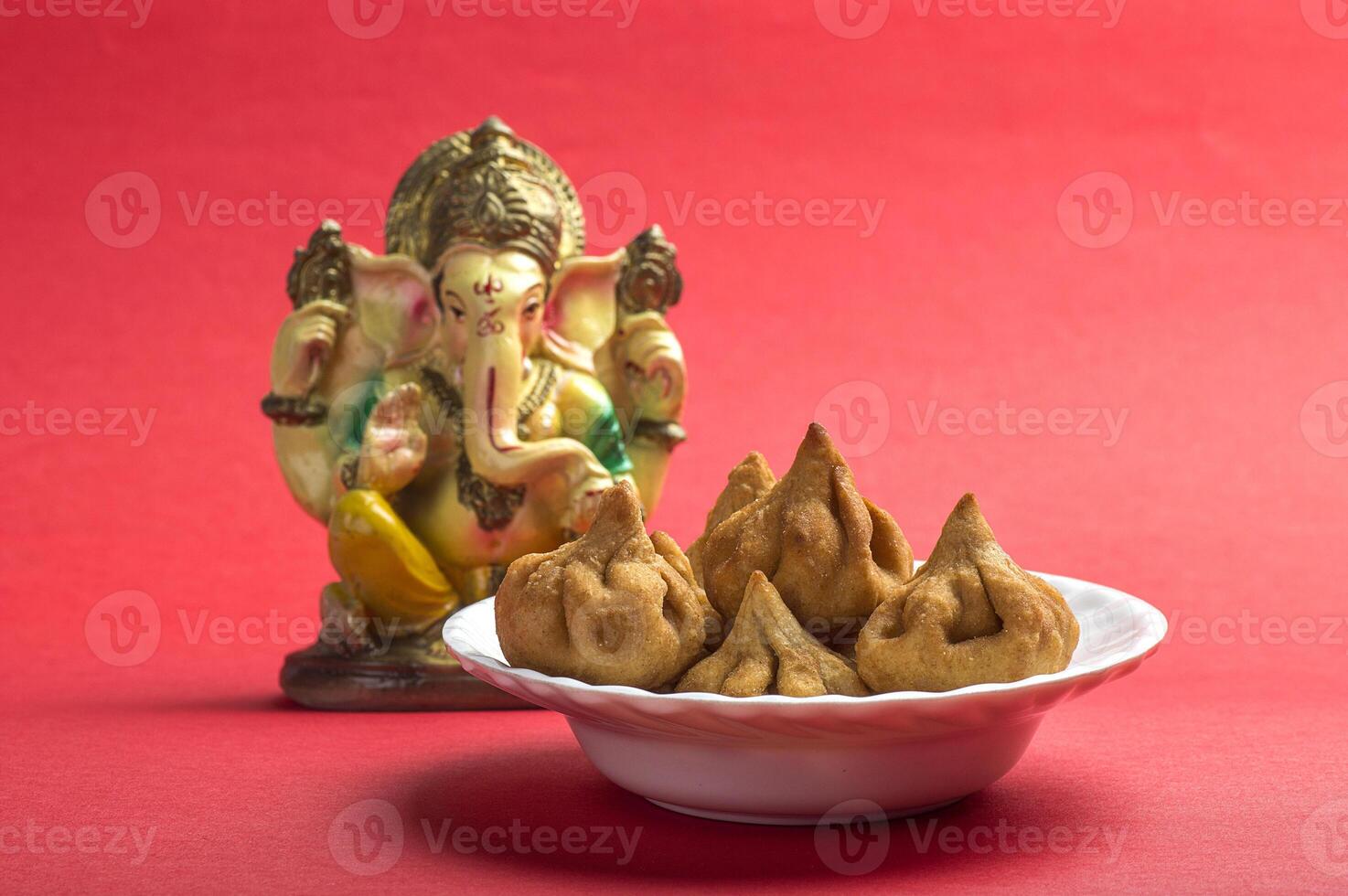 A bowl of food next to a statue of ganesh photo