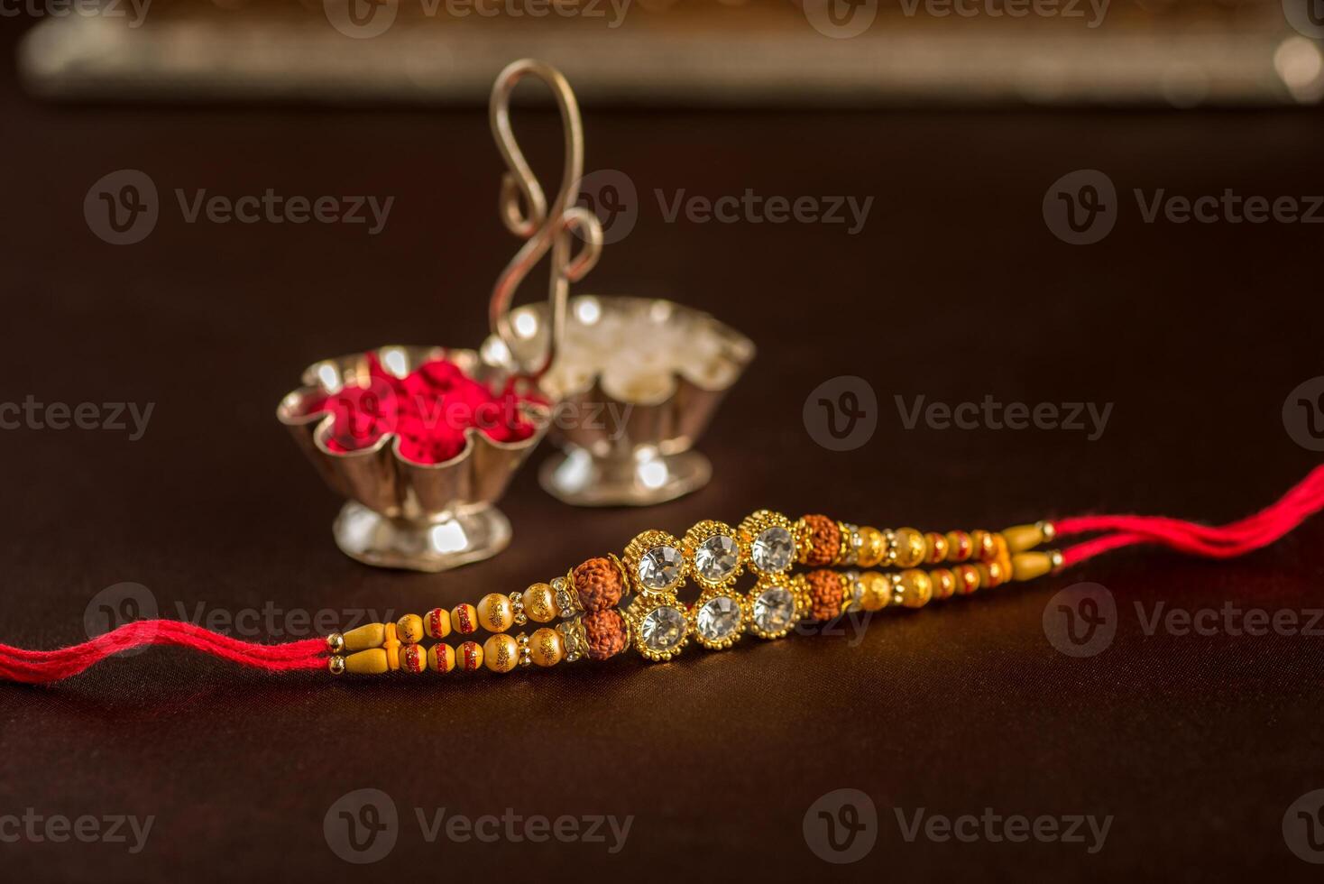 A rakhi with a red thread and a silver bowl photo