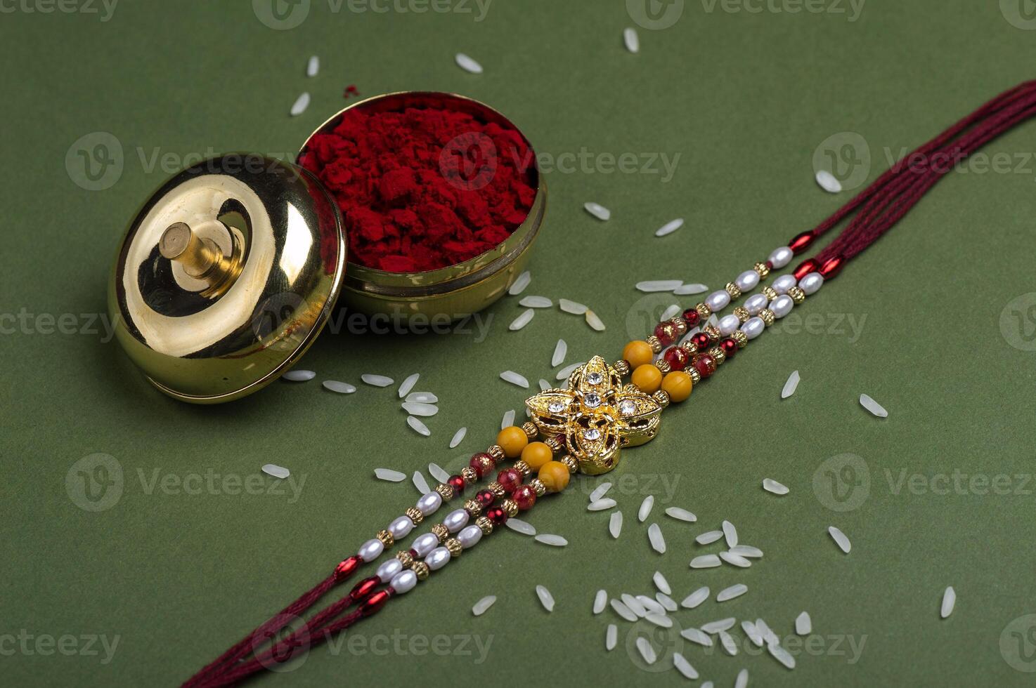 Indian festival Raksha Bandhan background with an elegant Rakhi, Rice Grains and Kumkum. A traditional Indian wrist band which is a symbol of love between Brothers and Sisters. photo