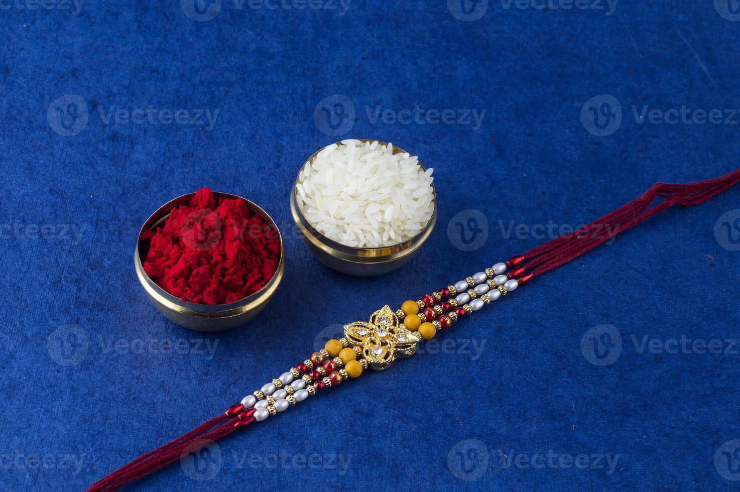 Indian festival Raksha Bandhan background with an elegant Rakhi, Rice Grains and Kumkum. A traditional Indian wrist band which is a symbol of love between Brothers and Sisters. photo