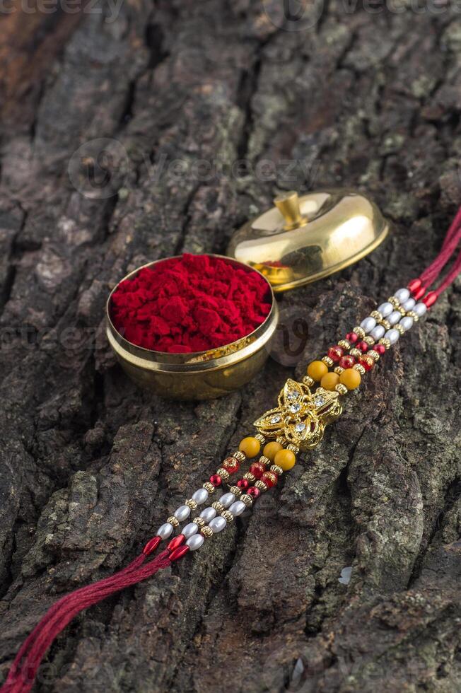 Indian festival Raksha Bandhan background with an elegant Rakhi, Rice Grains and Kumkum. A traditional Indian wrist band which is a symbol of love between Brothers and Sisters. photo