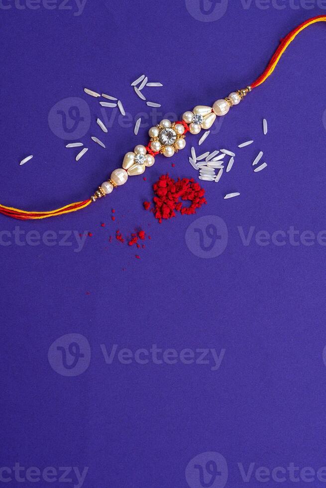Raksha Bandhan Rakhi with rice grains and kumkum. An Indian festive background. Traditional Indian wrist band which is a symbol of love between Brothers and Sisters. photo