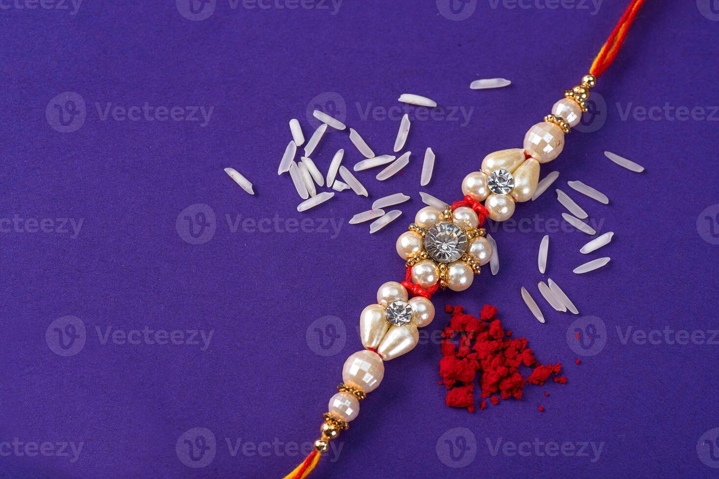 Raksha Bandhan Rakhi with rice grains and kumkum. An Indian festive background. Traditional Indian wrist band which is a symbol of love between Brothers and Sisters. photo