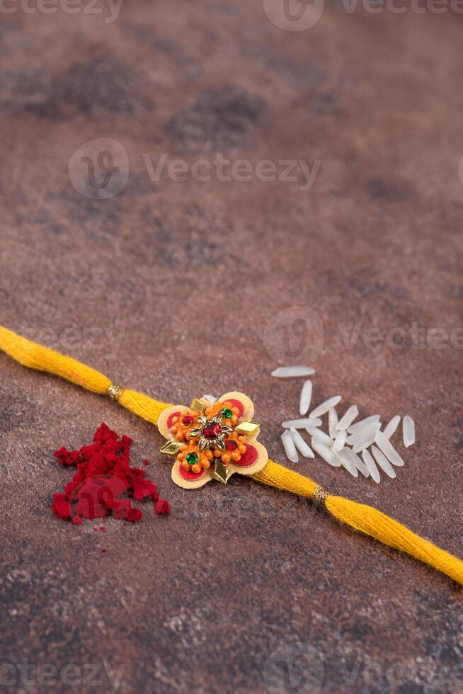 Raksha Bandhan Rakhi with rice grains and kumkum on stone background, Traditional Indian wrist band which is a symbol of love between Brothers and Sisters. photo