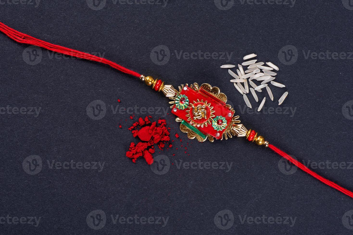 Raksha Bandhan Rakhi with rice grains and kumkum on black background, Traditional Indian wrist band which is a symbol of love between Brothers and Sisters. photo