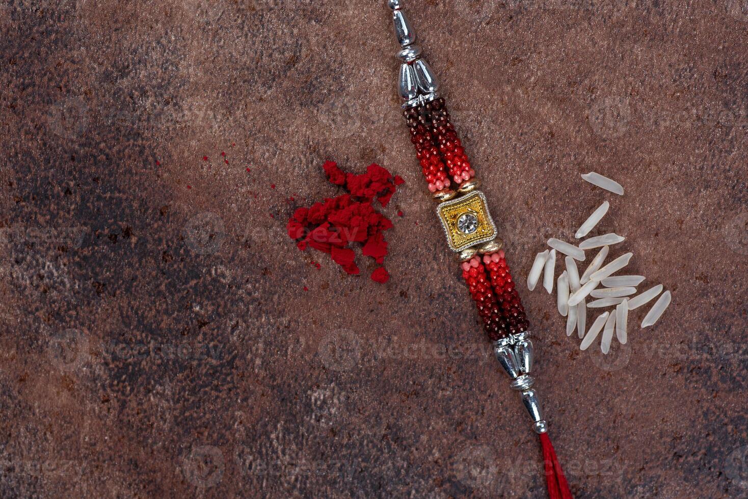 Raksha Bandhan Rakhi with rice grains and kumkum on stone background, Traditional Indian wrist band which is a symbol of love between Brothers and Sisters. photo