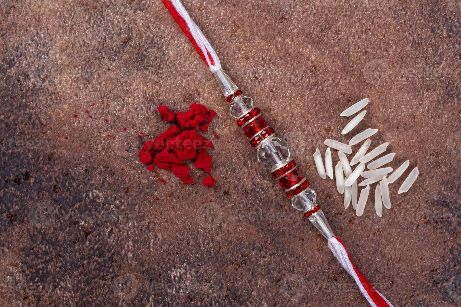 Raksha Bandhan Rakhi with rice grains and kumkum on stone background, Traditional Indian wrist band which is a symbol of love between Brothers and Sisters. photo