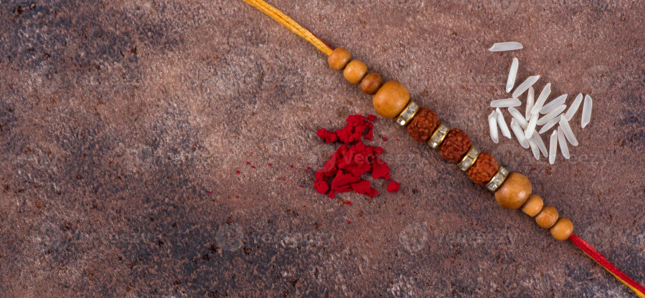 Raksha Bandhan Rakhi with rice grains and kumkum on stone background, Traditional Indian wrist band which is a symbol of love between Brothers and Sisters. photo