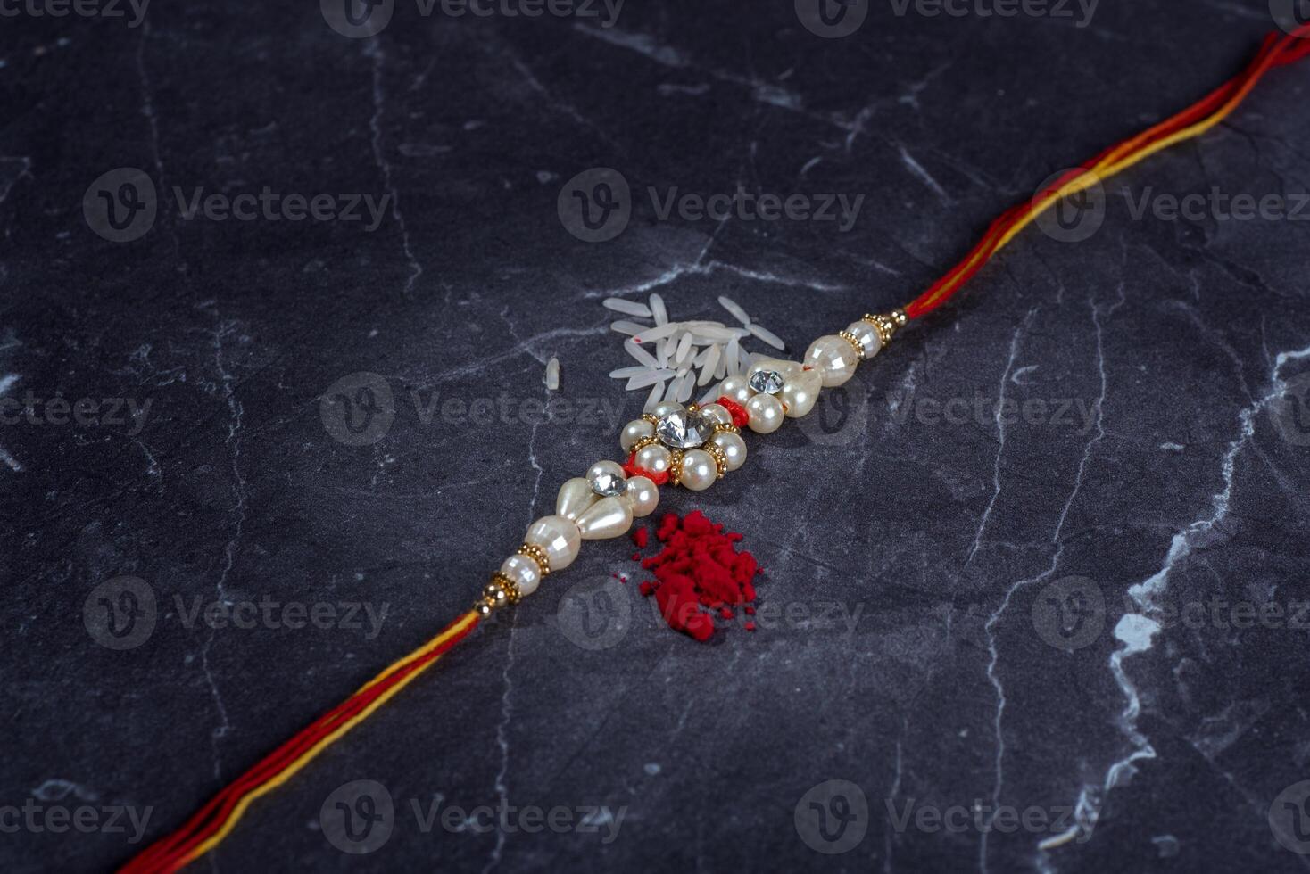 Raksha Bandhan Rakhi with rice grains and kumkum on stone background, Traditional Indian wrist band which is a symbol of love between Brothers and Sisters. photo