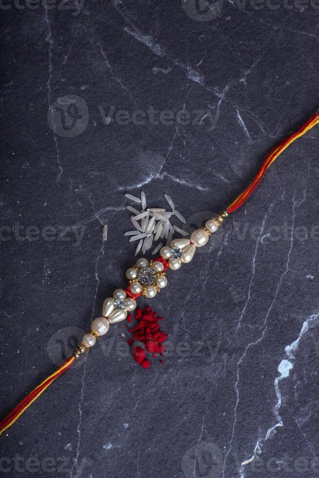 Raksha Bandhan Rakhi with rice grains and kumkum on stone background, Traditional Indian wrist band which is a symbol of love between Brothers and Sisters. photo