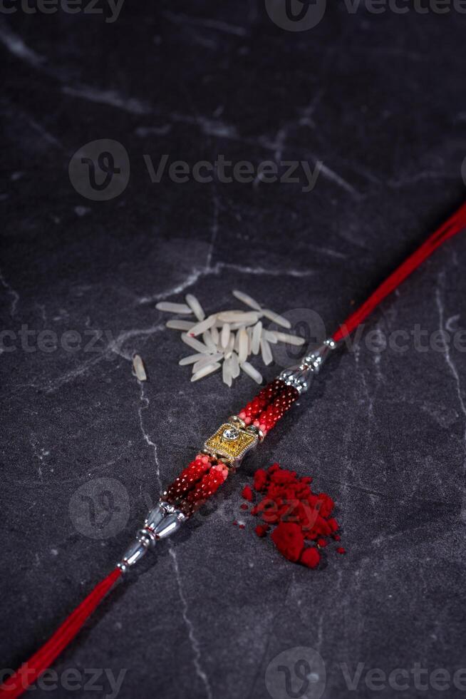 Raksha Bandhan Rakhi with rice grains and kumkum on stone background, Traditional Indian wrist band which is a symbol of love between Brothers and Sisters. photo