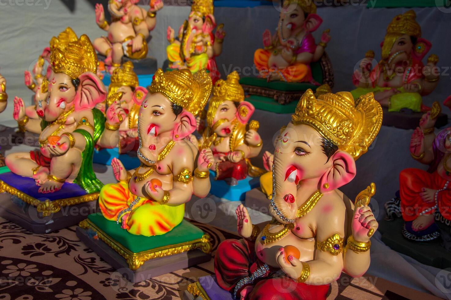 A group of colorful ganesh statues are displayed on a table photo
