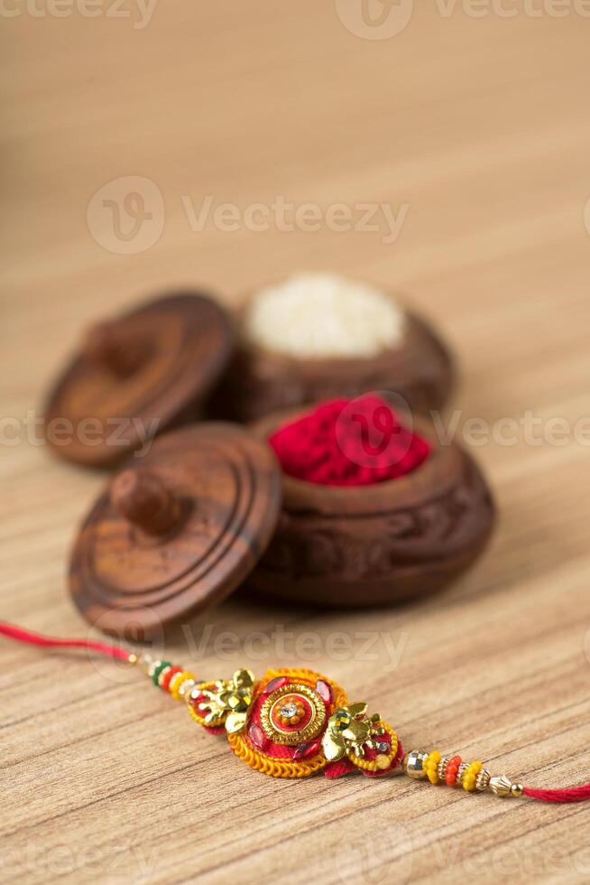 Indian festival Raksha Bandhan background with an elegant Rakhi, Rice Grains and Kumkum. A traditional Indian wrist band which is a symbol of love between Brothers and Sisters. photo