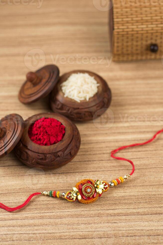 Indian festival Raksha Bandhan background with an elegant Rakhi, Rice Grains and Kumkum. A traditional Indian wrist band which is a symbol of love between Brothers and Sisters. photo