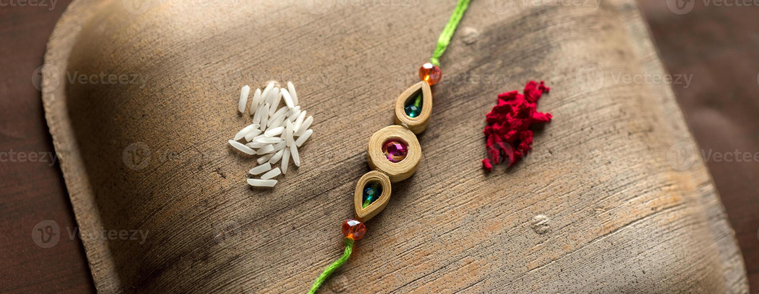 Indian festival Raksha Bandhan background with an elegant Rakhi, Rice Grains and Kumkum. A traditional Indian wrist band which is a symbol of love between Brothers and Sisters. photo