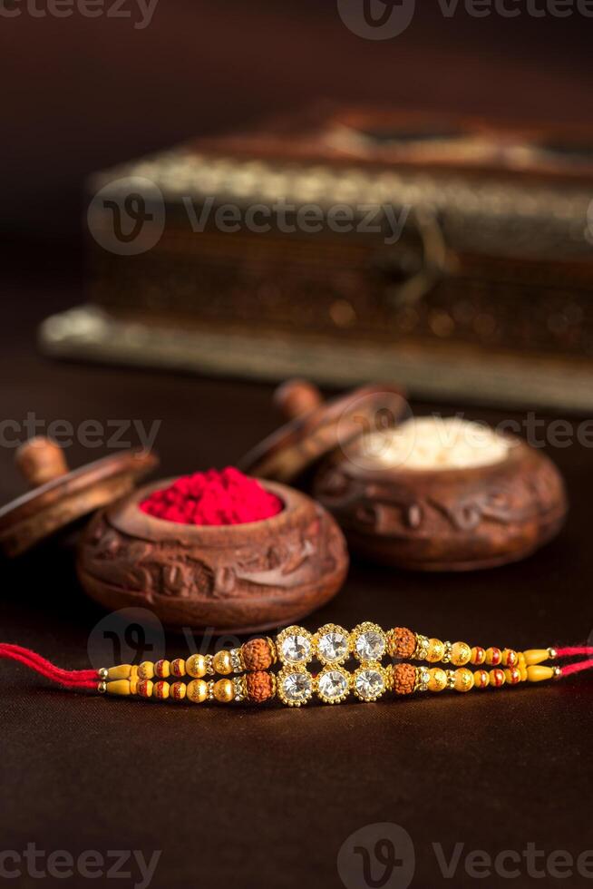 Indian festival Raksha Bandhan background with an elegant Rakhi, Rice Grains and Kumkum. A traditional Indian wrist band which is a symbol of love between Brothers and Sisters. photo