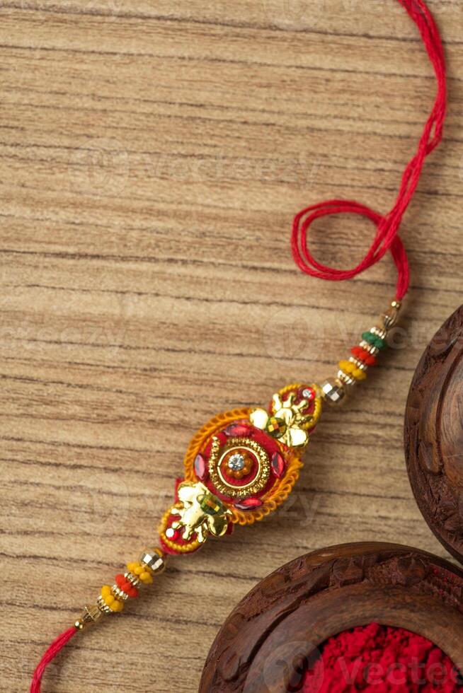Indian festival Raksha Bandhan background with an elegant Rakhi, Rice Grains and Kumkum. A traditional Indian wrist band which is a symbol of love between Brothers and Sisters. photo