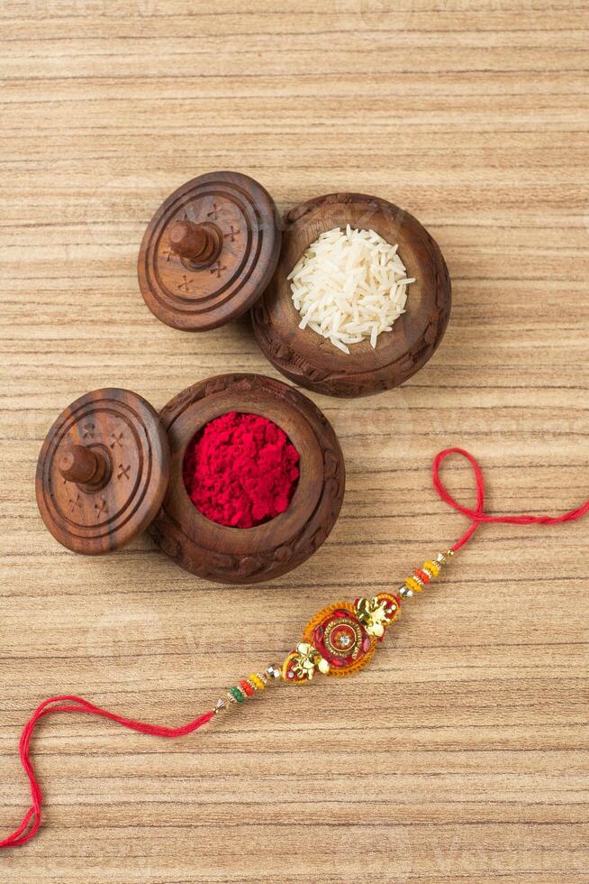 Indian festival Raksha Bandhan background with an elegant Rakhi, Rice Grains and Kumkum. A traditional Indian wrist band which is a symbol of love between Brothers and Sisters. photo