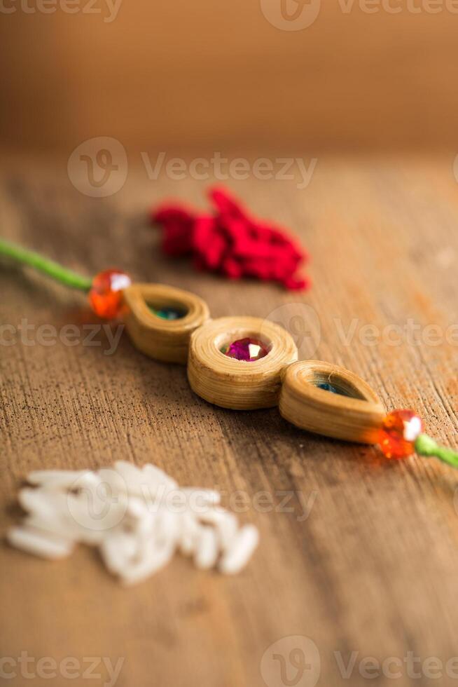Indian festival Raksha Bandhan background with an elegant Rakhi, Rice Grains and Kumkum. A traditional Indian wrist band which is a symbol of love between Brothers and Sisters. photo