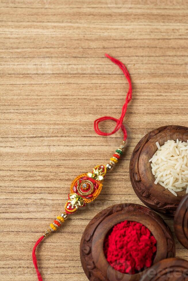 Indian festival Raksha Bandhan background with an elegant Rakhi, Rice Grains and Kumkum. A traditional Indian wrist band which is a symbol of love between Brothers and Sisters. photo