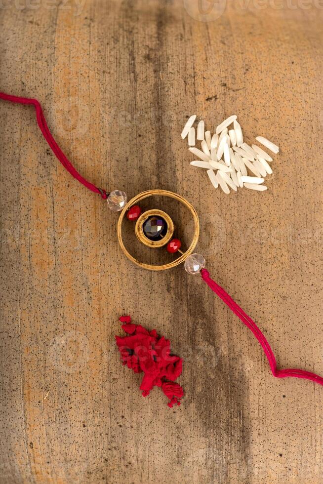 Indian festival Raksha Bandhan background with an elegant Rakhi, Rice Grains and Kumkum. A traditional Indian wrist band which is a symbol of love between Brothers and Sisters. photo
