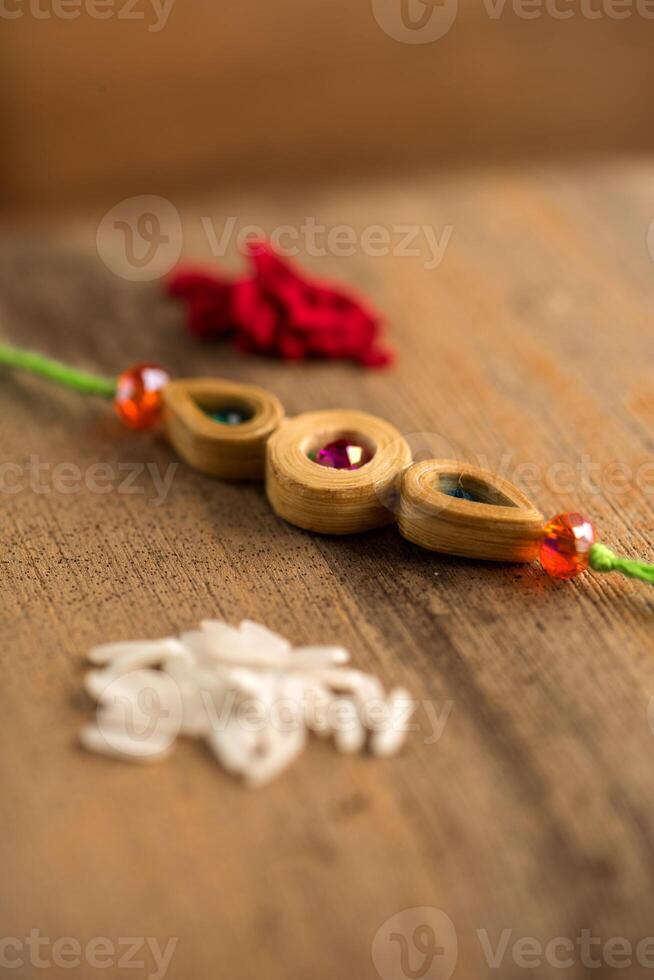 Indian festival Raksha Bandhan background with an elegant Rakhi, Rice Grains and Kumkum. A traditional Indian wrist band which is a symbol of love between Brothers and Sisters. photo