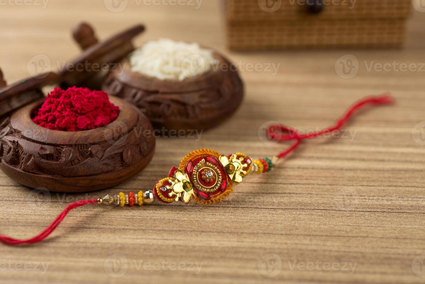 Indian festival Raksha Bandhan background with an elegant Rakhi, Rice Grains and Kumkum. A traditional Indian wrist band which is a symbol of love between Brothers and Sisters. photo