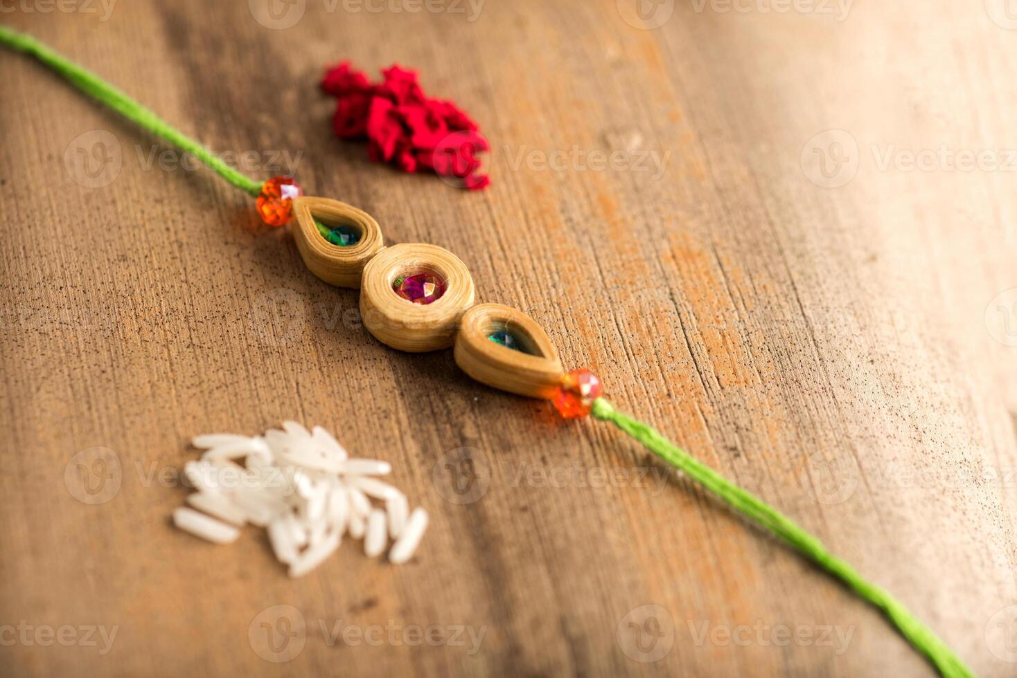Indian festival Raksha Bandhan background with an elegant Rakhi, Rice Grains and Kumkum. A traditional Indian wrist band which is a symbol of love between Brothers and Sisters. photo