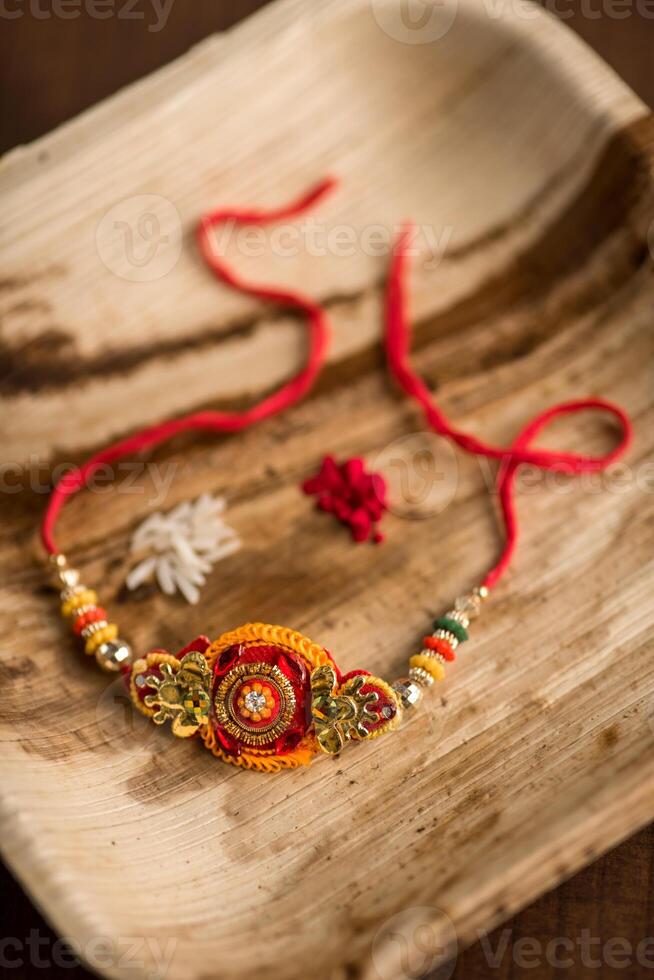 Indian festival Raksha Bandhan background with an elegant Rakhi, Rice Grains and Kumkum. A traditional Indian wrist band which is a symbol of love between Brothers and Sisters. photo