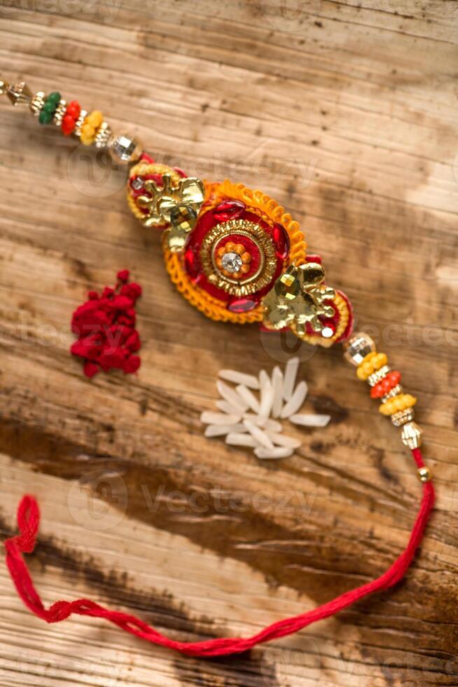 Indian festival Raksha Bandhan background with an elegant Rakhi, Rice Grains and Kumkum. A traditional Indian wrist band which is a symbol of love between Brothers and Sisters. photo