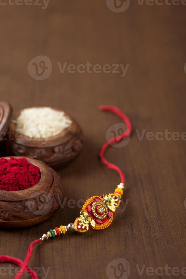 Indian festival Raksha Bandhan background with an elegant Rakhi, Rice Grains and Kumkum. A traditional Indian wrist band which is a symbol of love between Brothers and Sisters. photo