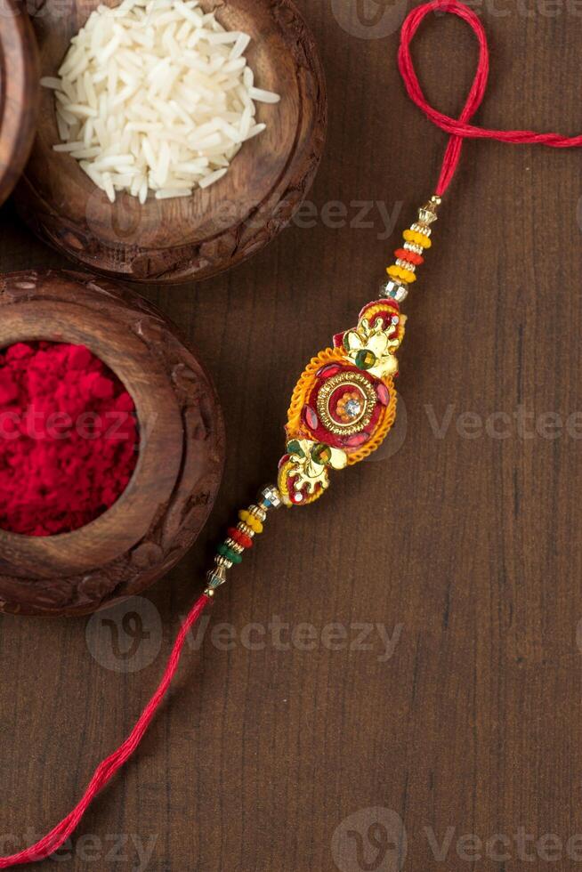 Indian festival Raksha Bandhan background with an elegant Rakhi, Rice Grains and Kumkum. A traditional Indian wrist band which is a symbol of love between Brothers and Sisters. photo