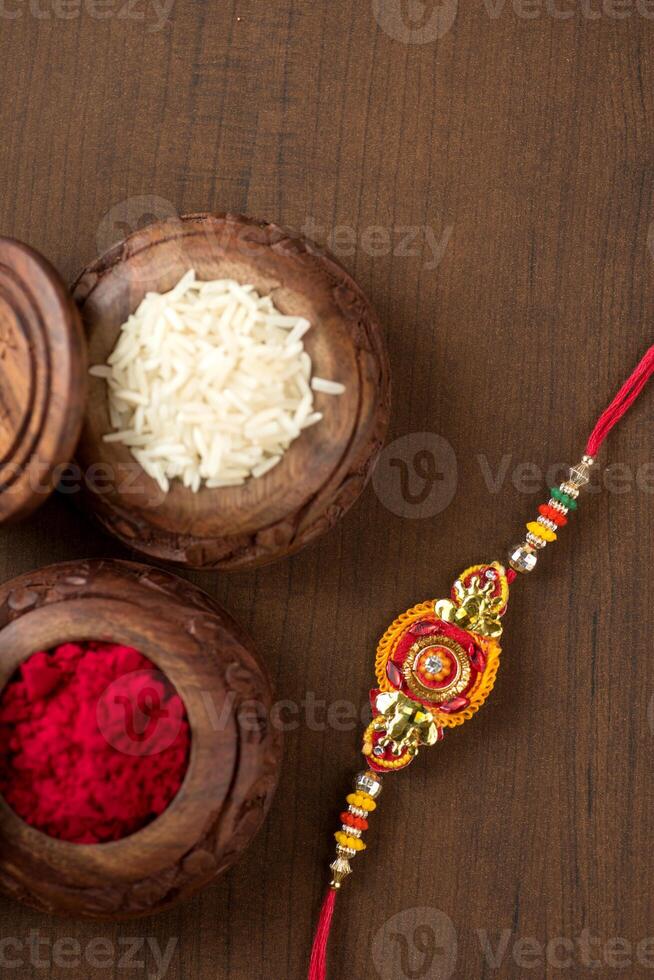Indian festival Raksha Bandhan background with an elegant Rakhi, Rice Grains and Kumkum. A traditional Indian wrist band which is a symbol of love between Brothers and Sisters. photo