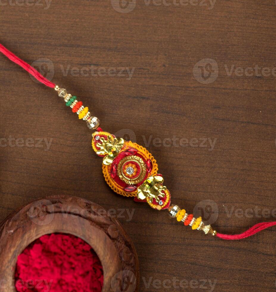 Indian festival Raksha Bandhan background with an elegant Rakhi, Rice Grains and Kumkum. A traditional Indian wrist band which is a symbol of love between Brothers and Sisters. photo