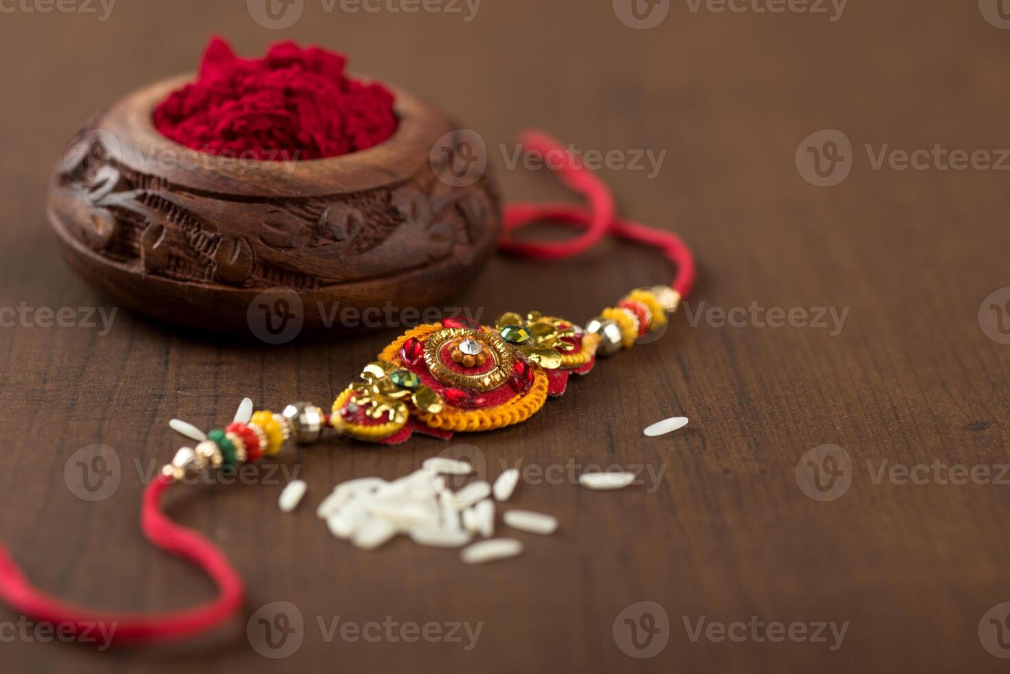 Indian festival Raksha Bandhan background with an elegant Rakhi, Rice Grains and Kumkum. A traditional Indian wrist band which is a symbol of love between Brothers and Sisters. photo