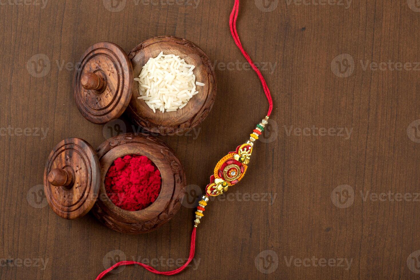 Indian festival Raksha Bandhan background with an elegant Rakhi, Rice Grains and Kumkum. A traditional Indian wrist band which is a symbol of love between Brothers and Sisters. photo
