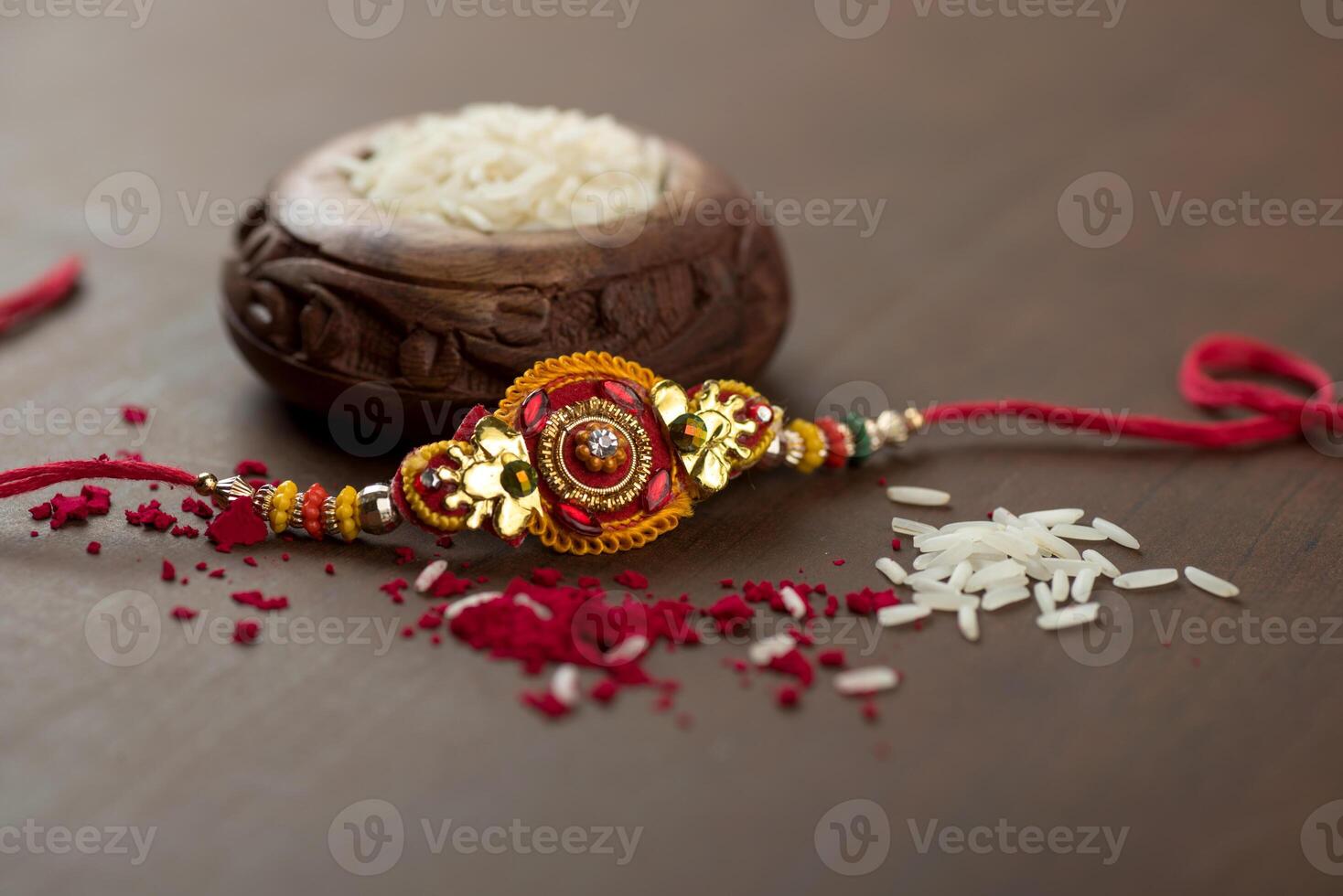 Indian festival Raksha Bandhan background with an elegant Rakhi, Rice Grains and Kumkum. A traditional Indian wrist band which is a symbol of love between Brothers and Sisters. photo