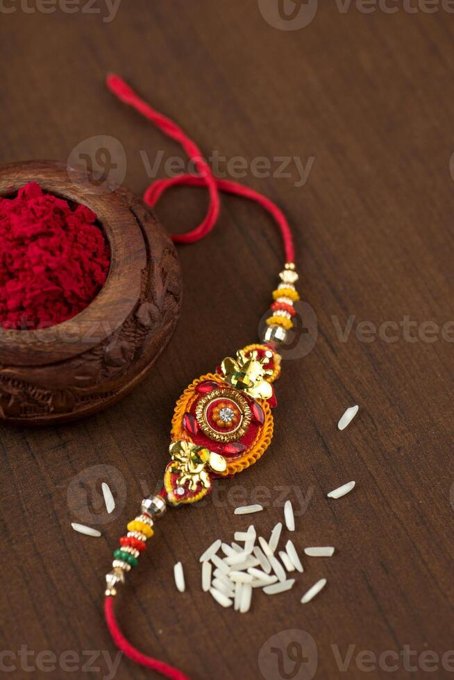 Indian festival Raksha Bandhan background with an elegant Rakhi, Rice Grains and Kumkum. A traditional Indian wrist band which is a symbol of love between Brothers and Sisters. photo
